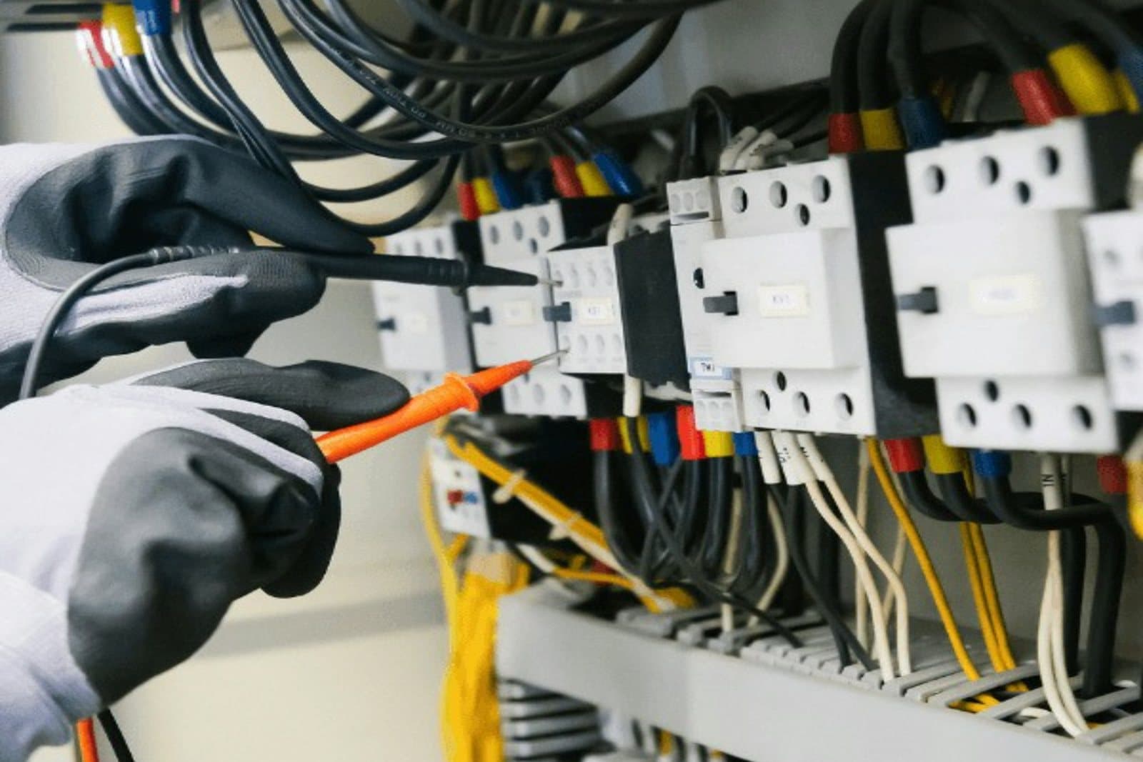 Techniker misst mit Prüfspitzen an Schützen in einem Schaltschrank